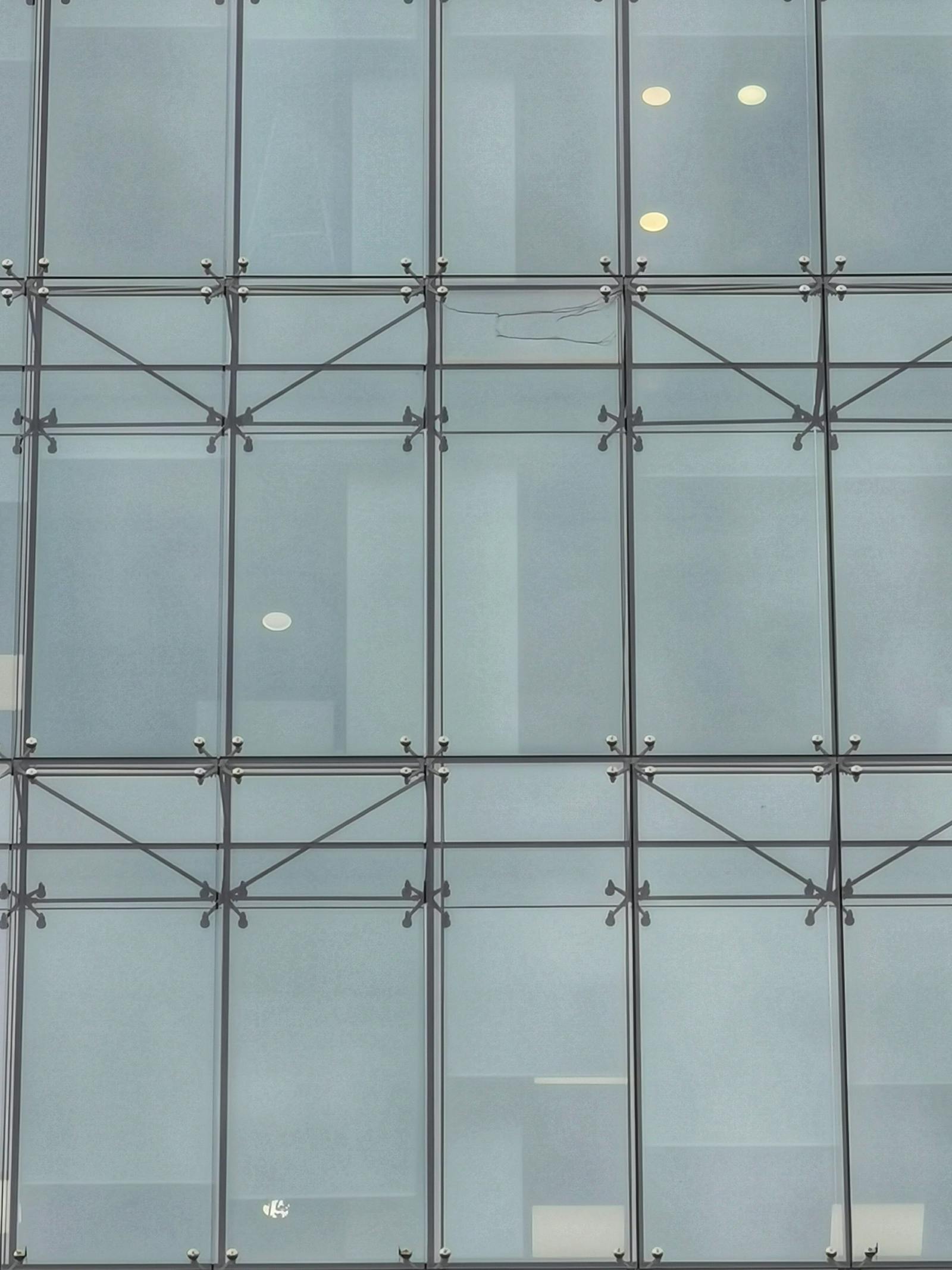 Modern glass facade with geometric patterns and metallic point-fix fittings
